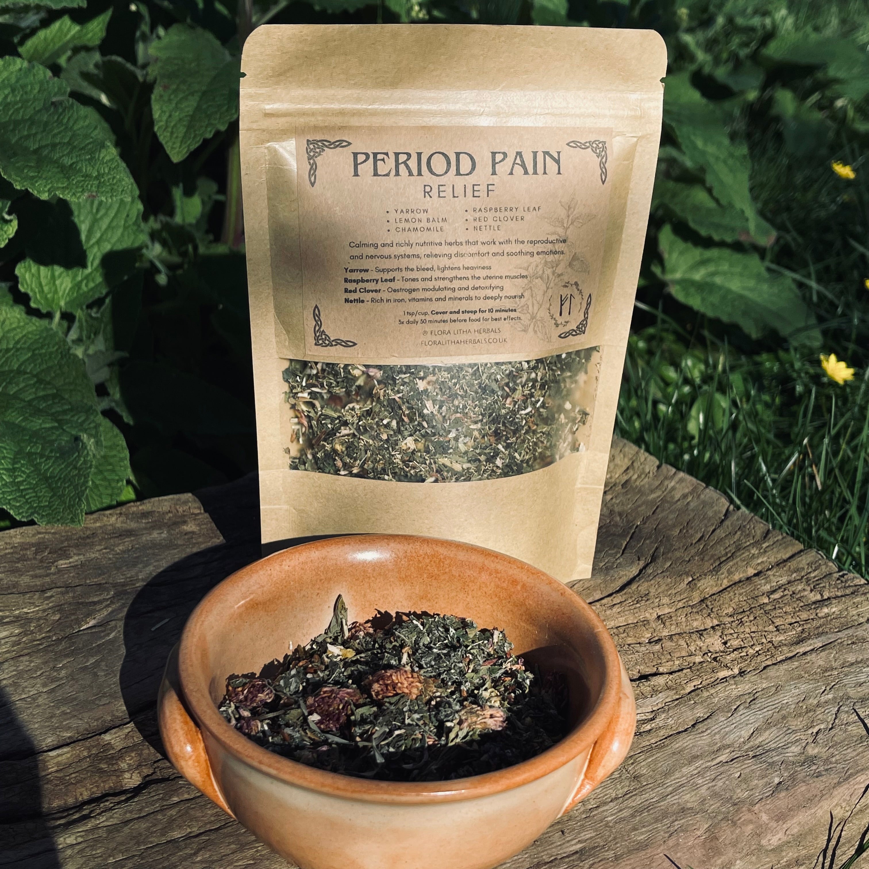 Tea package labeled 'Period Pain Relief' with a bowl of tea leaves on a wooden surface outdoors.