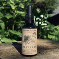 Bottle of Flora Litha Rest Easy herbal extract on a wooden surface with greenery in the background