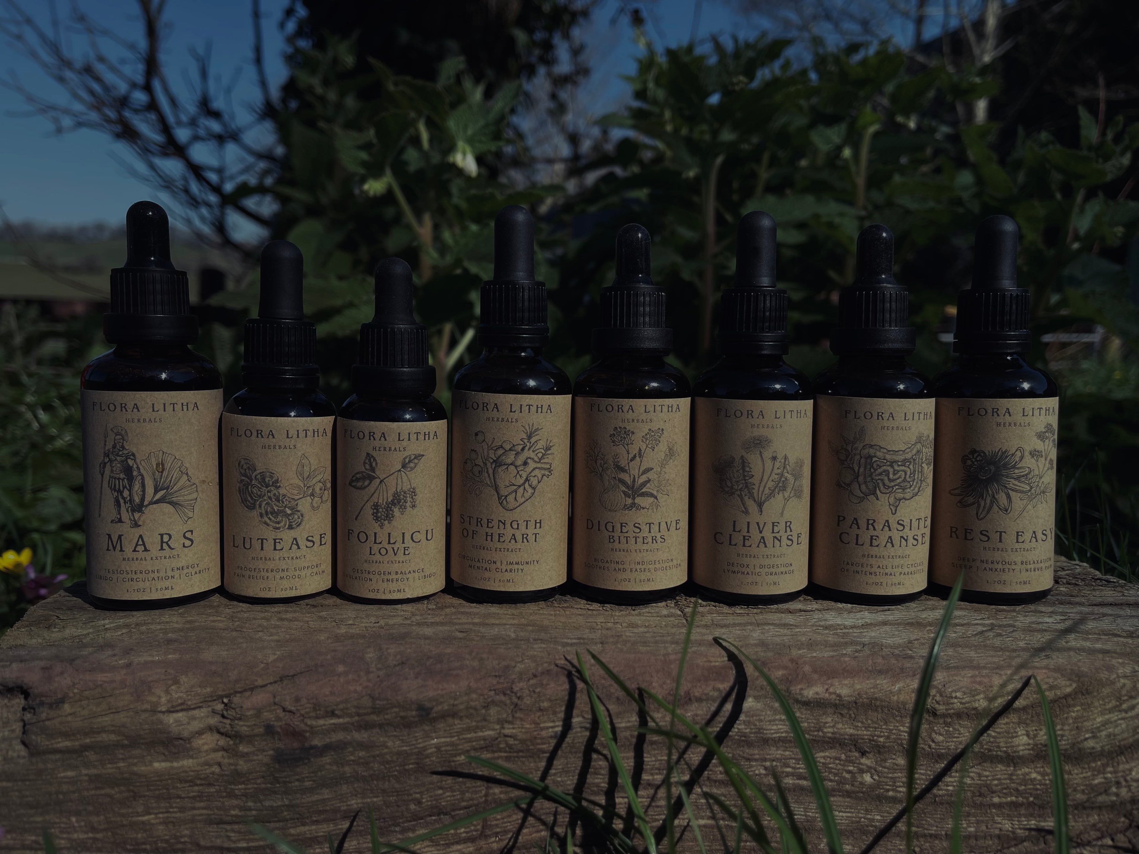 Row of tincture bottles with labels on a wooden surface outdoors